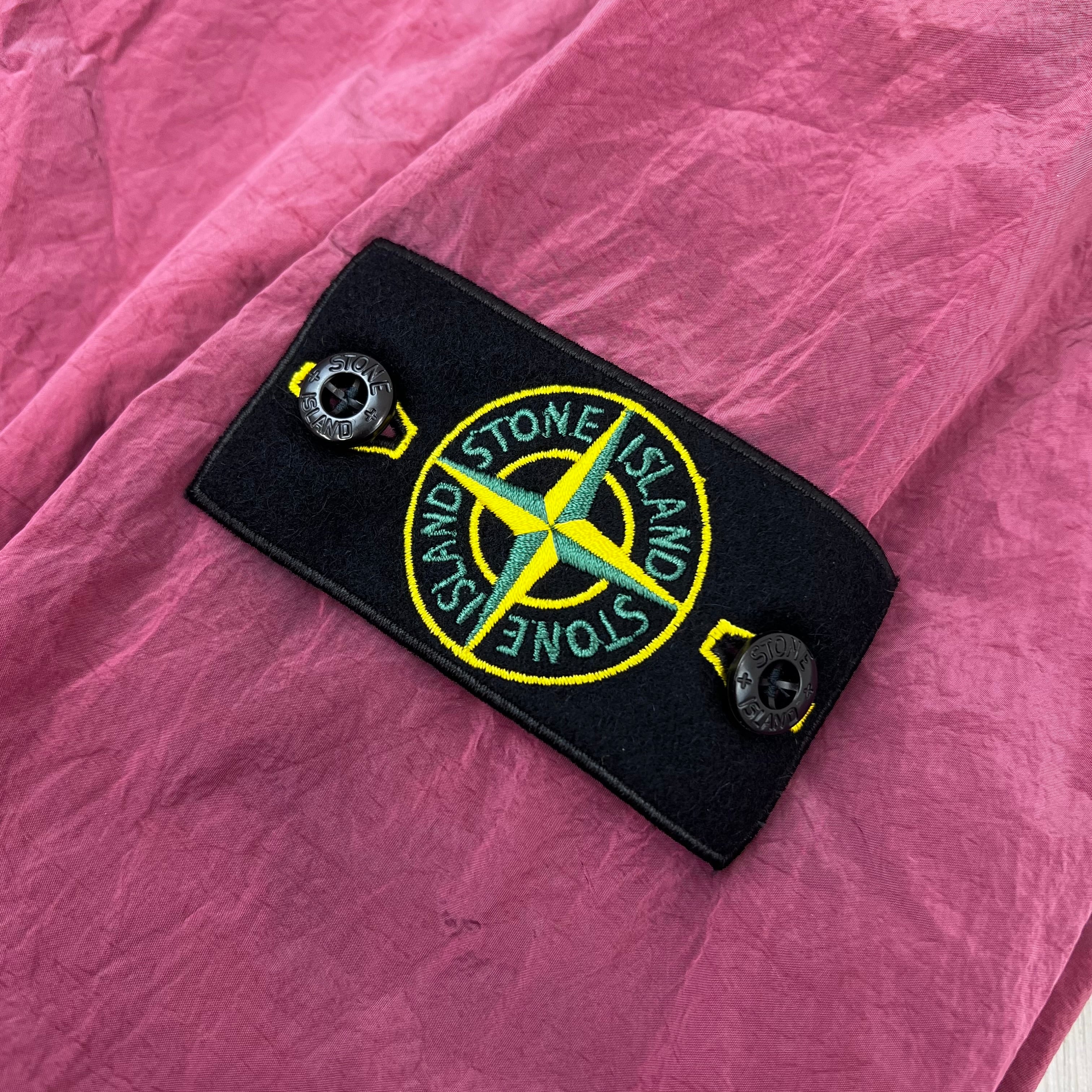 A close view of the compass badge on a Stone Island Nylon Metal Overshirt in Geranium.
